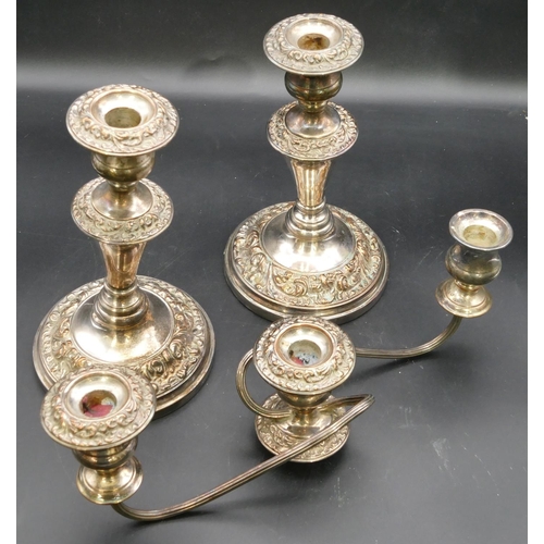 295 - A pair of Sheffield plated candlesticks on turned stems with round sweeping bases, all over embossed... 