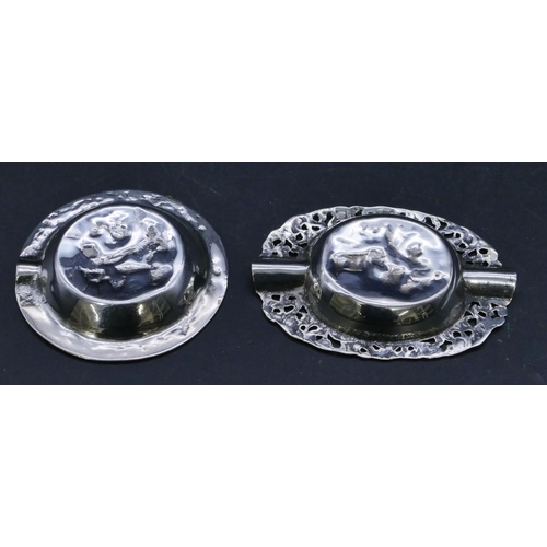 303 - 2 Continental silver coloured metal small ashtrays with embossed figure decoration, largest 7.5cm wi... 