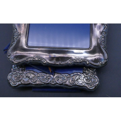 318 - A silver plated rectangular scallop shaped freestanding photograph frame with embossed floral and sc... 