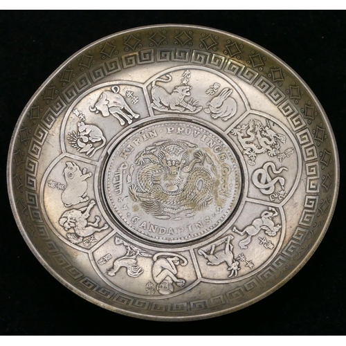 356 - A small circular Oriental dish inset with coin with raised animal motifs, 9.3cm diameter.