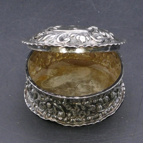 369 - A late Victorian silver round pill box with hinged lid and all over embossed floral and scroll decor... 