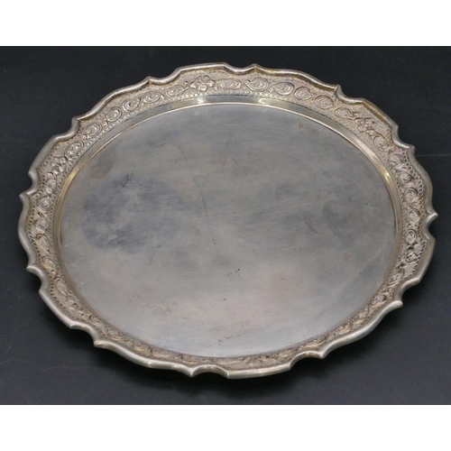 378 - An Eastern silver coloured metal round card tray with scallop shaped and embossed rim with floral an... 