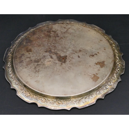 378 - An Eastern silver coloured metal round card tray with scallop shaped and embossed rim with floral an... 