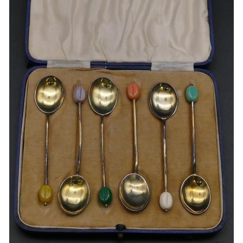 406 - A Harlequin set of 6 silver gilt and multi-coloured enamelled coffee bean spoons in fitted blue leat... 