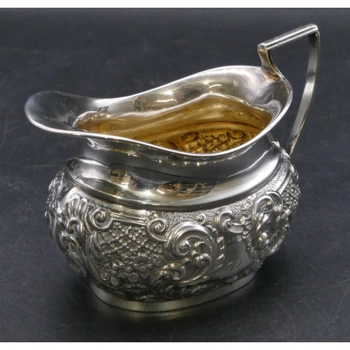 407 - A Victorian silver cream jug with embossed floral, leaf and scroll decoration, Chester 1899, makers ... 