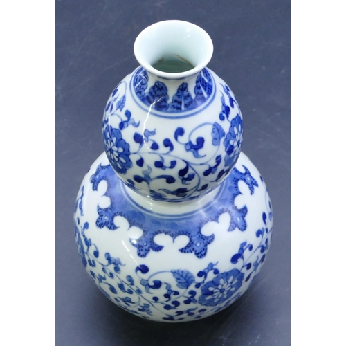 41 - An Oriental double gourd blue and white vase with allover floral, leaf and scroll decoration, 18cm h... 