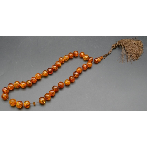 432 - An amber bead necklace with cord tassel, 88.5 grams gross.