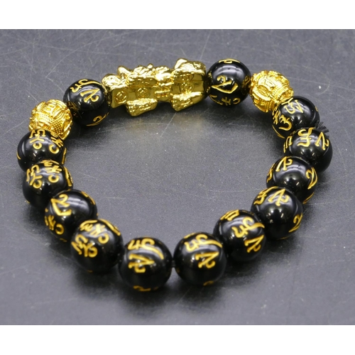 447 - An Oriental black and gilt bead bracelet with dragon motif.