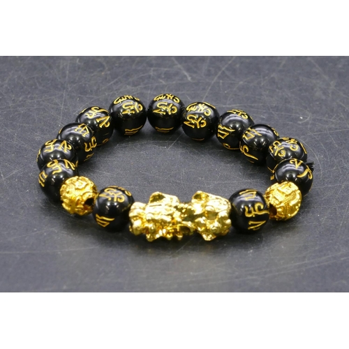 447 - An Oriental black and gilt bead bracelet with dragon motif.