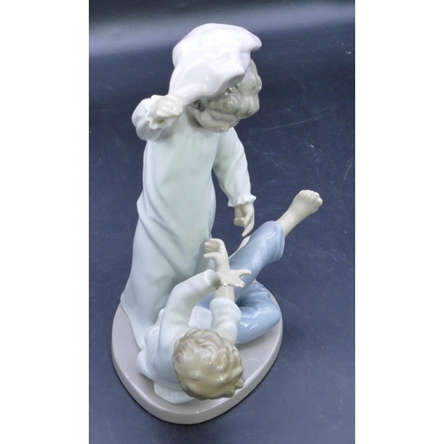 53 - A Nao group of a young girl and boy having a pillow fight, 24.5cm high.