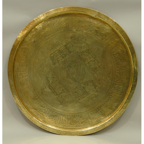 771 - An Eastern round brass tray with engraved decoration on folding carved hard wood stand, 63.5cm diame... 