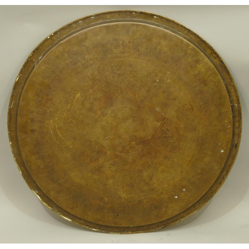 771 - An Eastern round brass tray with engraved decoration on folding carved hard wood stand, 63.5cm diame... 