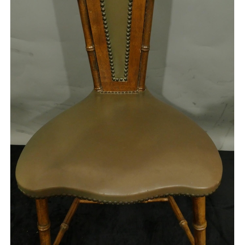 775 - A mahogany hall chair with a narrow carved back, leather overstuffed seat and part back on round tur... 