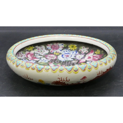 87 - An Oriental round shallow bowl on white and black ground with multi-coloured dragon, floral and leaf... 