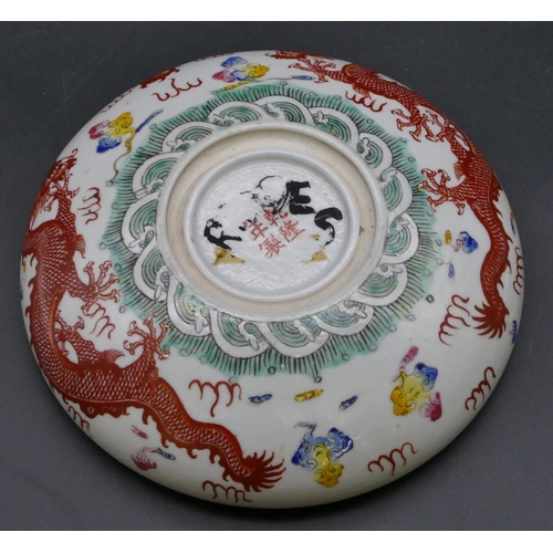 87 - An Oriental round shallow bowl on white and black ground with multi-coloured dragon, floral and leaf... 