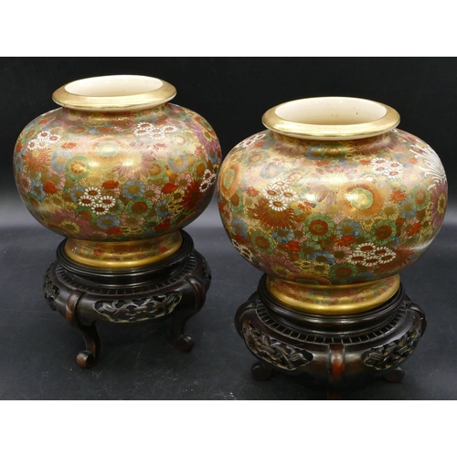 88 - A pair of signed satsuma round bulbous thin necked vases with hardwood stands, on multi-coloured gro... 