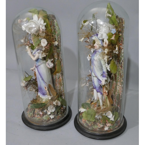 100 - A pair of Bisque china figures of gentleman and lady on blue and white ground, mounted under glass d... 