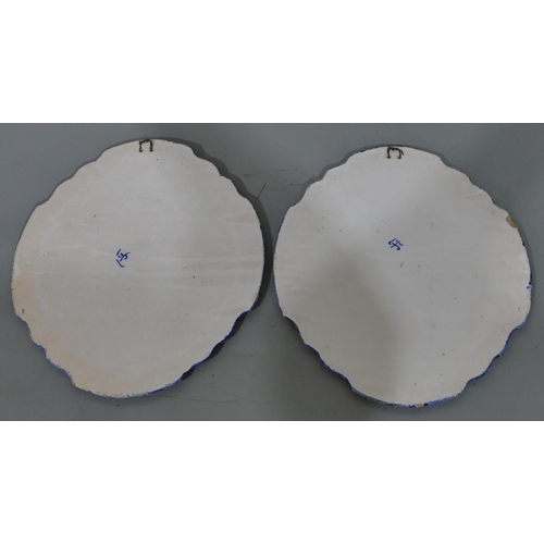 104 - A pair of Delft oval scallop shaped hanging plaques on blue and white ground depicting river landsca... 