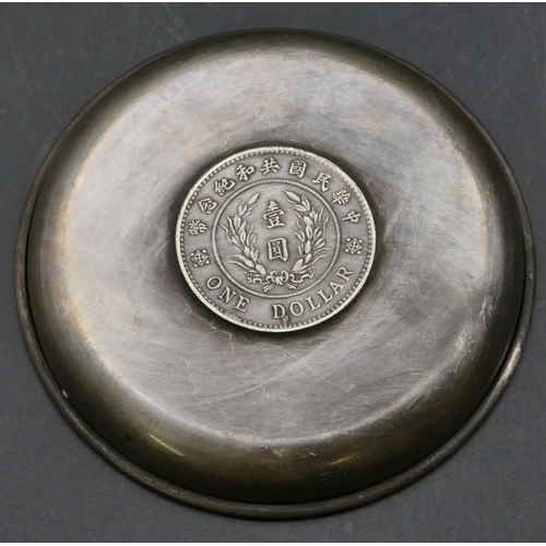 222 - An Oriental circular dish inset with Oriental 1 dollar coin, 10.6cm diameter.