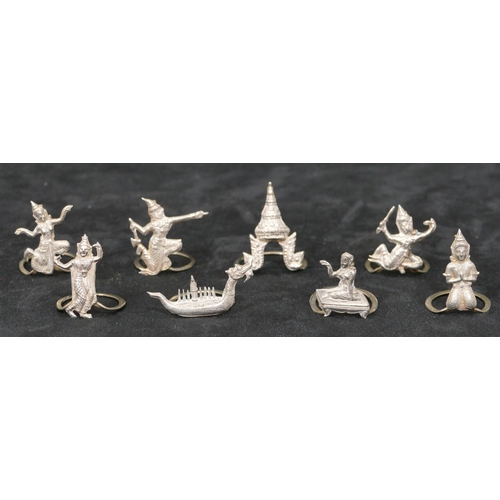 281 - 8 Eastern silver coloured metal menu holders in the form of figures, buildings, boats etc.