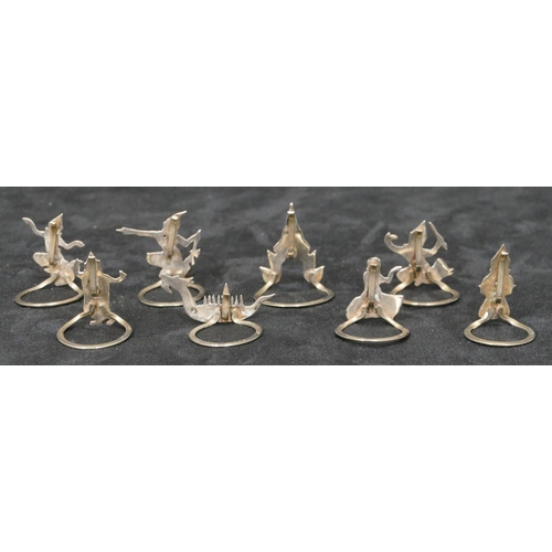 281 - 8 Eastern silver coloured metal menu holders in the form of figures, buildings, boats etc.