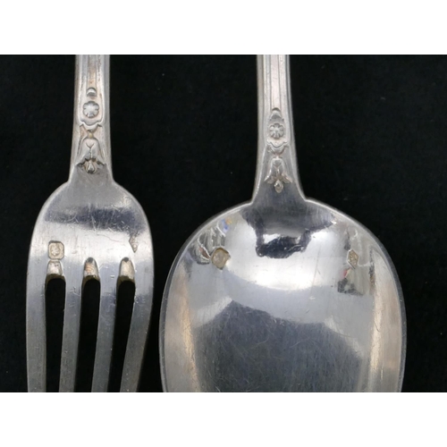 300 - A pair of Continental silver coloured metal christening spoon and fork with raised scroll and leaf d... 