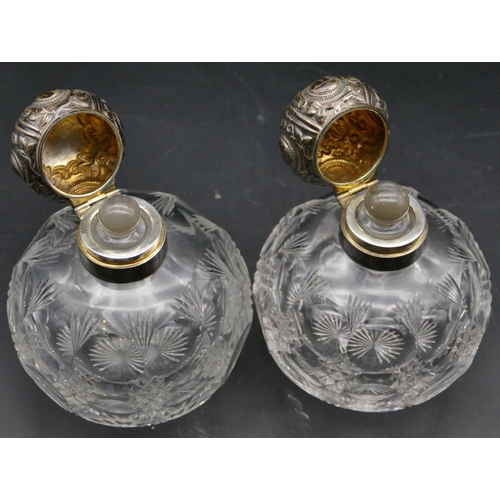 358 - A pair of George V heavy cut glass round bulbous shaped scent bottles with silver necks, hinged lids... 