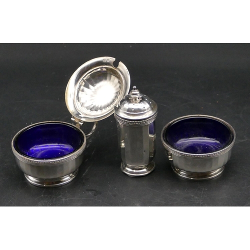 371 - A 3 piece Birmingham silver condiment set with chamfer decoration, lidded mustard pot with blue glas... 