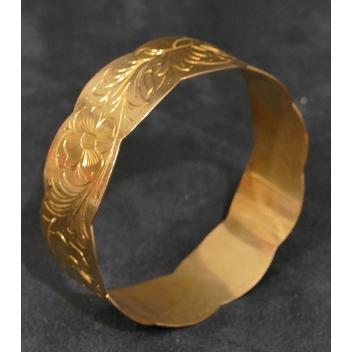 445 - A high carat gold bangle with scallop shaped rims, engraved with floral and leaf decoration, inner m... 