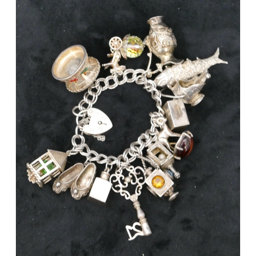 455 - A silver bracelet with padlock clasp, mounted with 13 charms, 88.5 grams