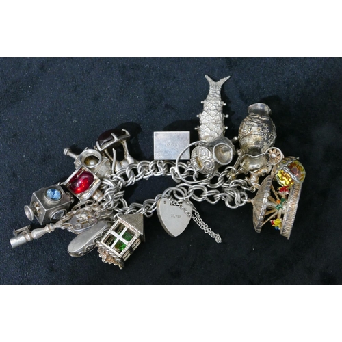 455 - A silver bracelet with padlock clasp, mounted with 13 charms, 88.5 grams