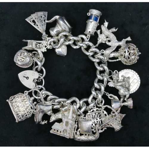 456 - A silver bracelet with padlock clasp, mounted with 17 charms, 139.6 grams