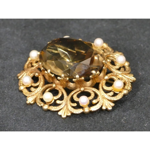 457 - A 9ct gold oval brooch with centre smoky quartz and surrounded by half pearls and pierced decoration... 