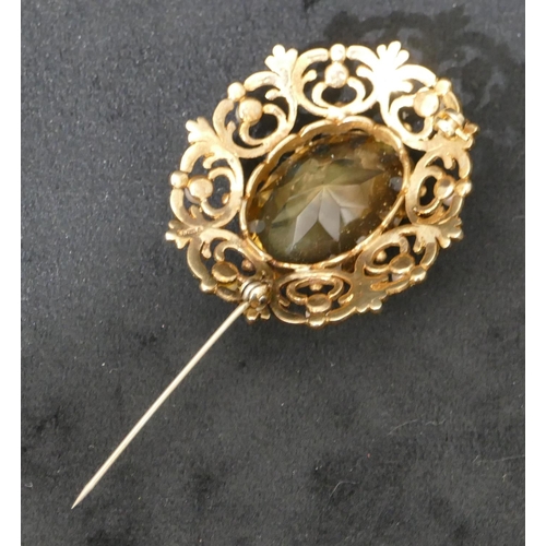 457 - A 9ct gold oval brooch with centre smoky quartz and surrounded by half pearls and pierced decoration... 