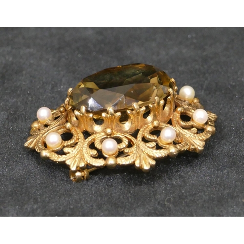 457 - A 9ct gold oval brooch with centre smoky quartz and surrounded by half pearls and pierced decoration... 