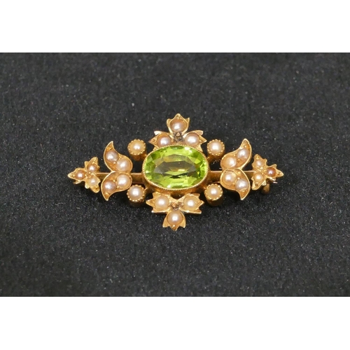 492 - A 15ct gold brooch set with centre green stone surrounded by half pearls, 3.2cm long