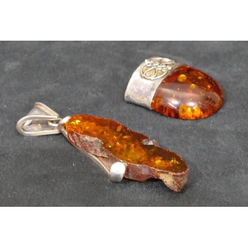 504 - A silver and amber drop pendant, 8cm long and another silver and amber drop pendant. (2)