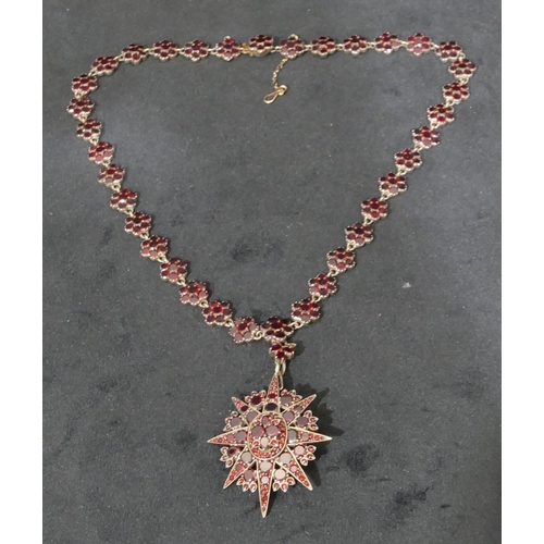 512 - A Victorian silver and garnet star shaped pendant brooch with matching silver and garnet chain, 44cm... 