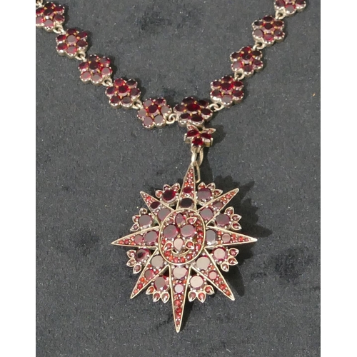 512 - A Victorian silver and garnet star shaped pendant brooch with matching silver and garnet chain, 44cm... 