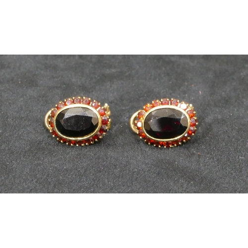 517 - A pair of 14ct gold oval earrings set with garnets and surrounded by smaller garnets, 2.2cm high, 12... 