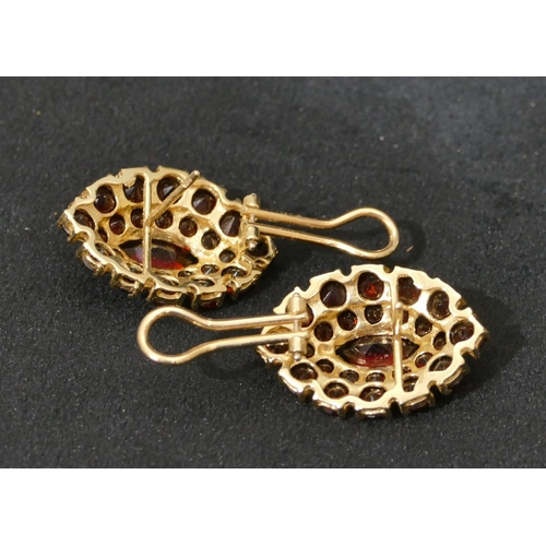 519 - A pair of 14ct oval gold earrings set with centre garnets and surrounded by smaller garnets, 3cm hig... 