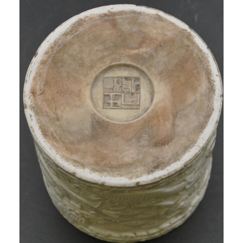 53 - An Oriental round brush pot with raised dragon and fish decoration, 11cm high.