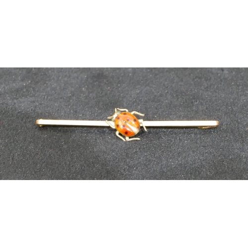 534 - A 9ct gold bar brooch mounted with enamelled ladybird motif, 5cm long, 2.1 grams gross.