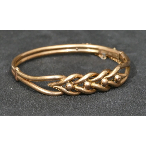 559 - A 9ct gold hinged bangle with pierced twist top mounted with ball motifs, 10.7 grams.