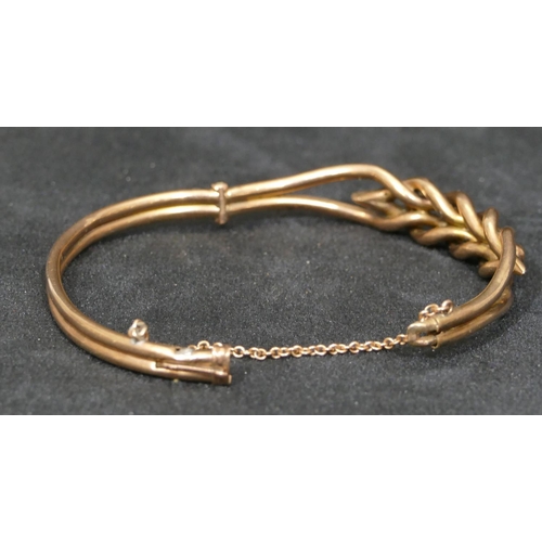 559 - A 9ct gold hinged bangle with pierced twist top mounted with ball motifs, 10.7 grams.