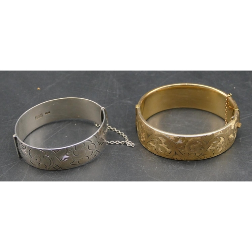 562 - A silver hinged bangle with engraved decoration and a gold covered hinged bangle. (2)