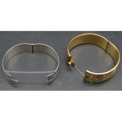 562 - A silver hinged bangle with engraved decoration and a gold covered hinged bangle. (2)