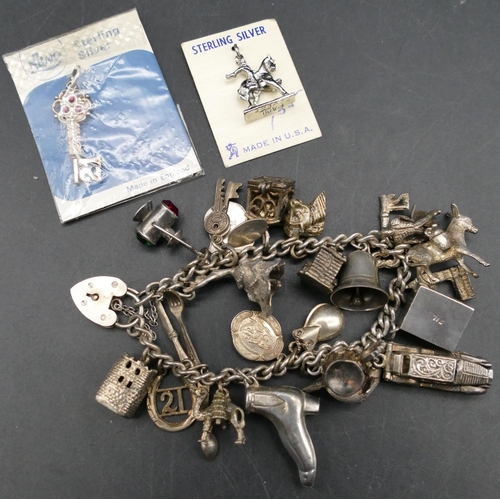 567 - A silver linked bracelet with padlock clasp, mounted with 21 various charms, 72.3 grams gross.