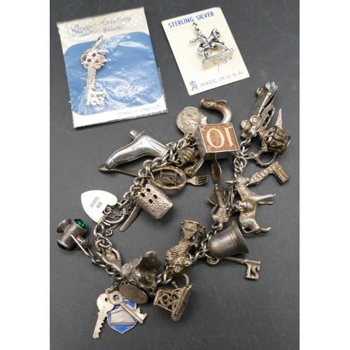 567 - A silver linked bracelet with padlock clasp, mounted with 21 various charms, 72.3 grams gross.