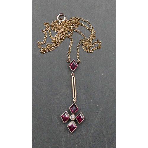 617 - A 9ct gold drop pendant with chain set with reddish/purple stones and centre half pearl, 42.5cm long... 